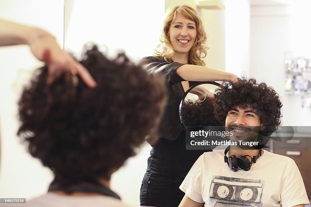 Young man with buckled hair and hairdresser