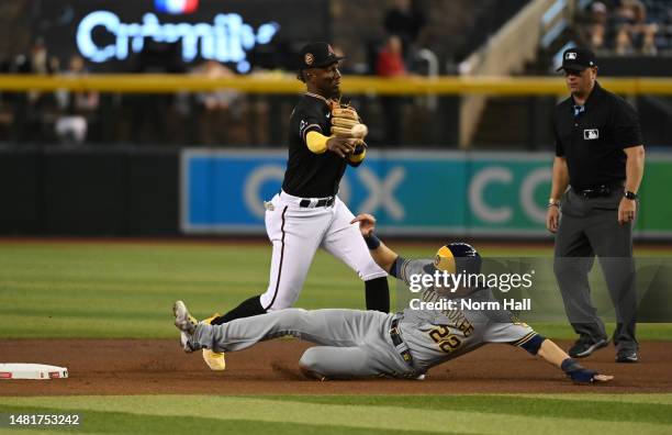 Geraldo Perdomo of the Arizona Diamondbacks turns a double play on a ground ball hit by Rowdy Tellez of the Milwaukee Brewers as Christian Yelich is...