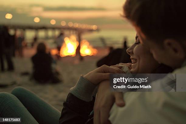 young couple hugging at campfire - couple sunset stockfoto's en -beelden