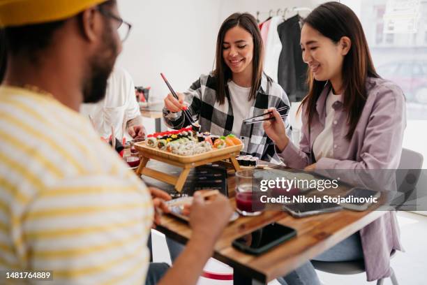 young couple enjoying sushi at the local sushi restaurant - japanese food stock pictures, royalty-free photos & images