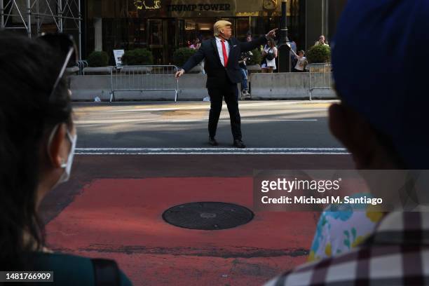 An impersonator of former President Donald Trump pretends to direct traffic outside of Trump Tower ahead of the former president's arrival on April...