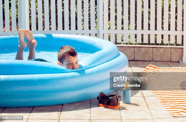 boy in the blue inflatable rubber pool - inflatable swimming pool stock pictures, royalty-free photos & images