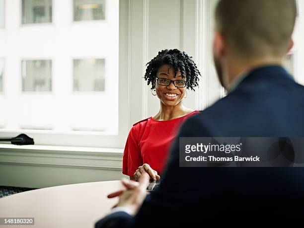 coworkers in discussion at table in office - woman in black suit stock pictures, royalty-free photos & images