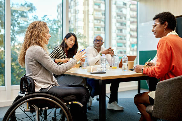 Woman in a wheelchair leading a discussion in an office setting.