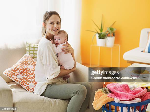 mom holding baby - mum sitting down with baby stockfoto's en -beelden