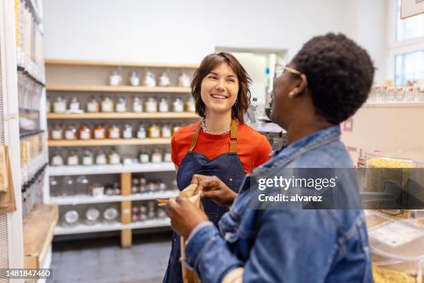 eco-friendly grocery shop owner assisting a female customer - saleswoman stock pictures, royalty-free photos & images