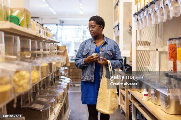 african woman customer buying groceries in zero waste store - empty super market shelf stock pictures, royalty-free photos & images