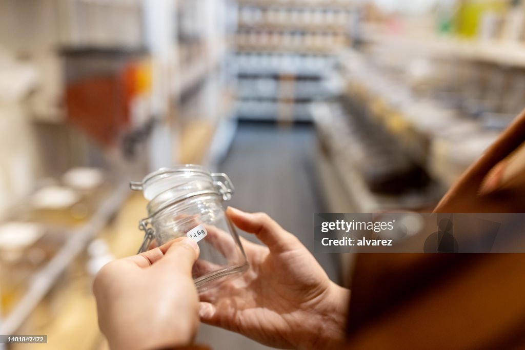 Close-up of a woman labelling a container at zero waste store
