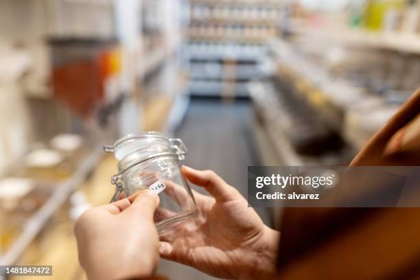 close-up of a woman labelling a container at zero waste store - labeling stockfoto's en -beelden