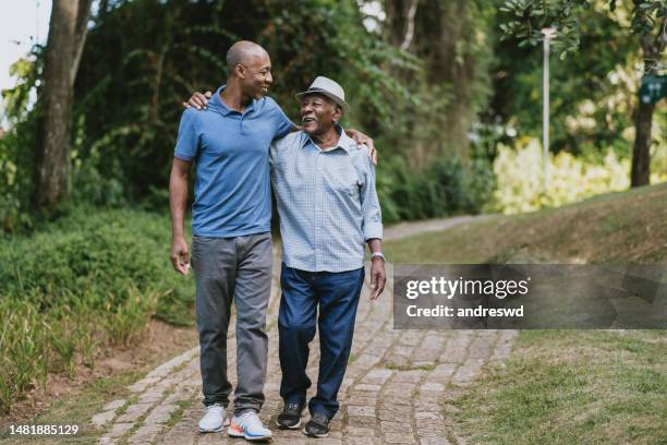 portrait of elderly father and adult son walking - adults walking stockfoto's en -beelden