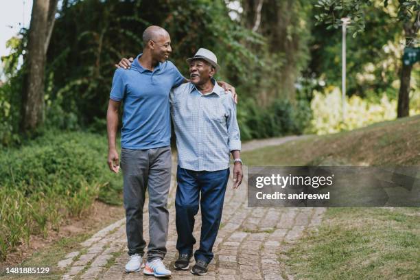 portrait of elderly father and adult son walking - two people hugging full body stock pictures, royalty-free photos & images
