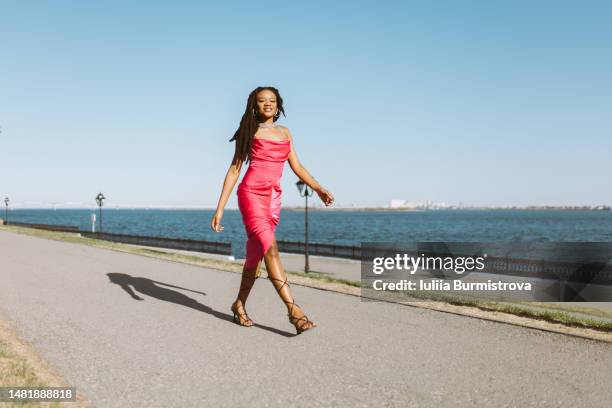 a gorgeous fashion model walking along the sea embankment - ärmelloses kleid stock-fotos und bilder