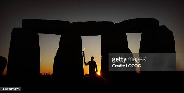 In this handout image provided by LOCOG, Olympic gold medalist former sprinter Torchbearer 001 Michael Johnson holds the Olympic Flame at Stonehenge...
