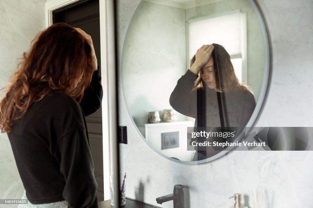 Depressed Woman Looks in Bathroom Mirror