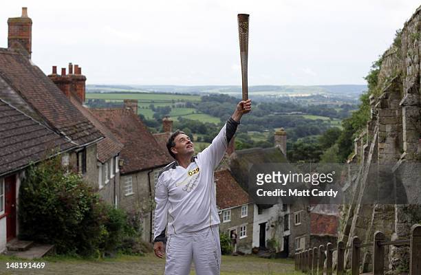 Torchbearer Alan Surtees, carries the Olympic Flame up Gold Hill as the Torch Relay on day 55 of the London 2012 Olympic Torch Relay on July 12, 2012...