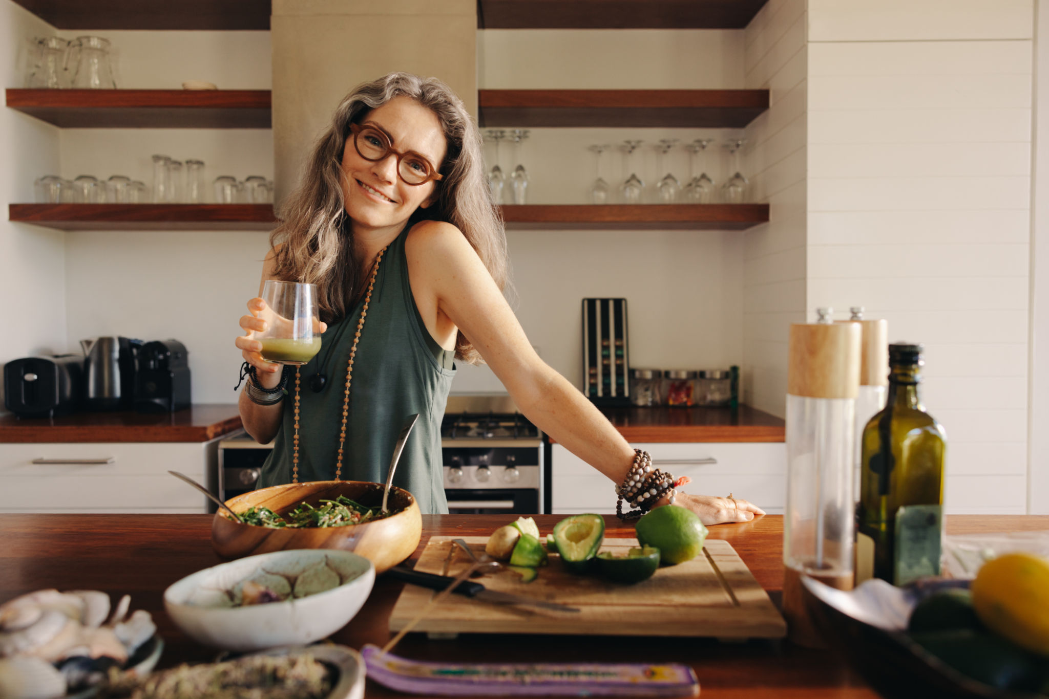 Mujer vegetariana sosteniendo un vaso de jugo verde en su cocina Mujer vegetariana sosteniendo un vaso de jugo verde en su cocina