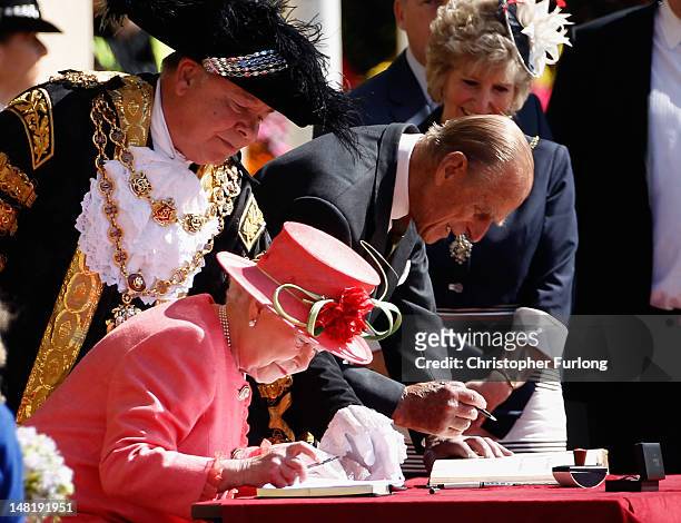 Queen Elizabeth II and Prince Philip, Duke of Edinburgh, sign the visitors book in Victoria Square, during her Diamond Jubilee visit to the City on...
