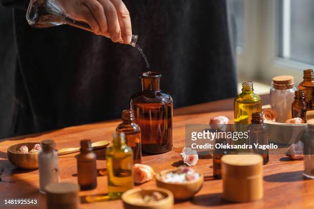 woman preparing aromatic liquid for diffuser on wooden table. homemade perfume from essential flower oil. - parfumeur créateur photos et images de collection