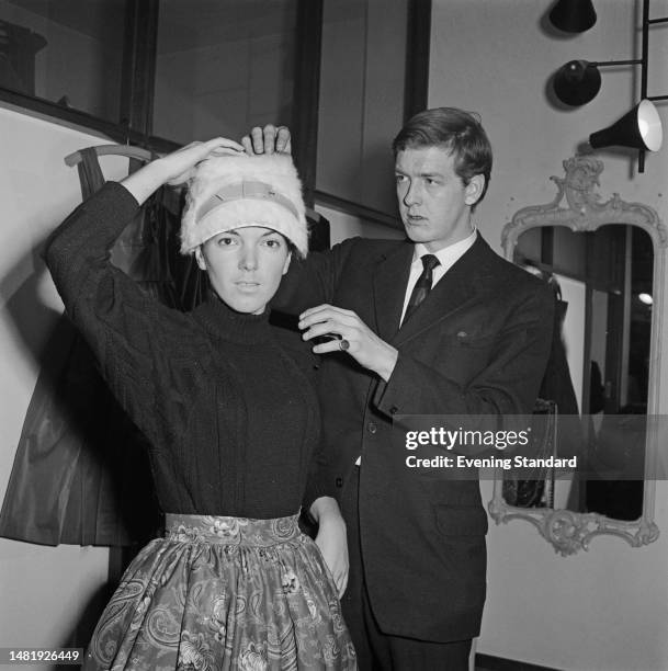 English fashion designer Mary Quant trying on a hat, with her husband and business partner Alexander Plunkett-Greene at their boutique 'Bazaar' on...