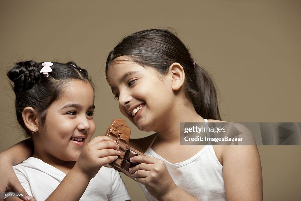 Retrato de estudio de dos hermanas (frecuencia de 6-11 comiendo chocolate)