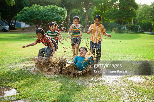 kids (4-7) playing in puddle of water - girls wrestling stockfoto's en -beelden