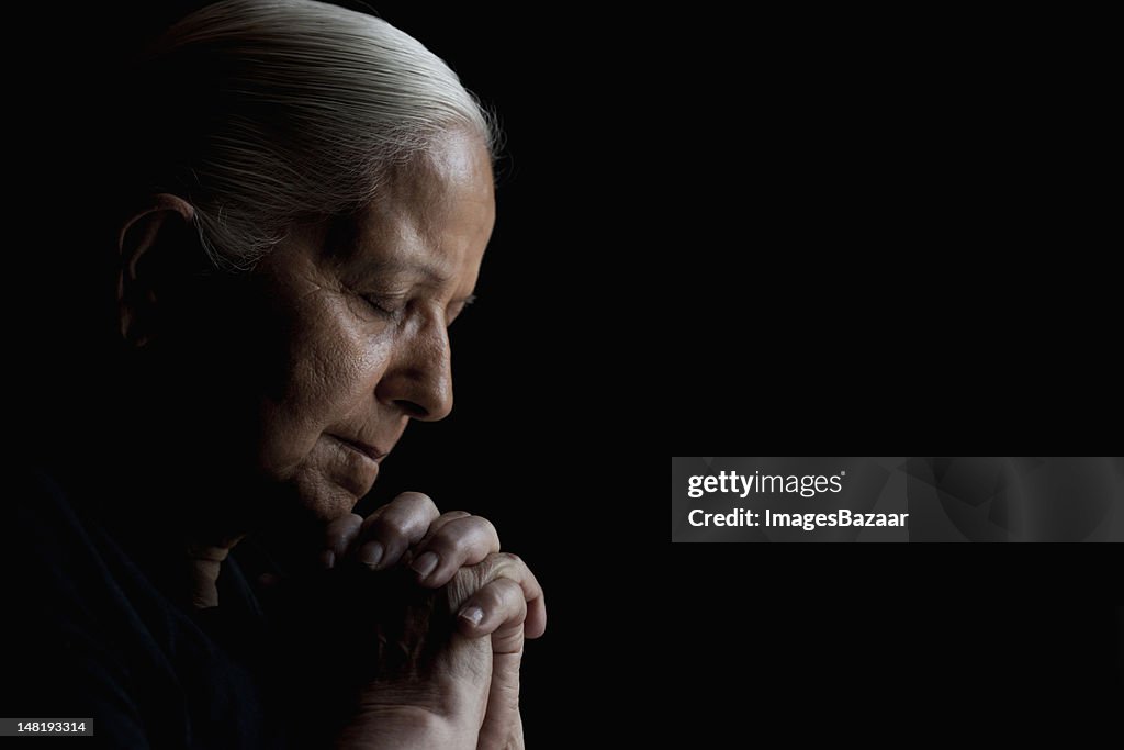 Studio shot of senior woman praying