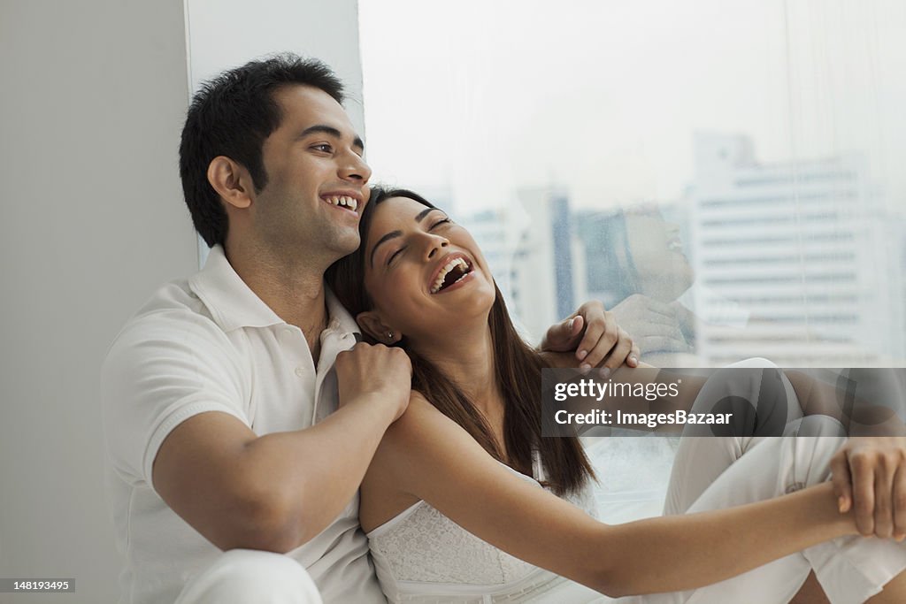 Young couple sitting by window and laughing