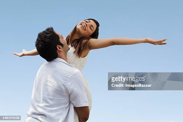happy young couple playing against blue sky - india couple lift stock pictures, royalty-free photos & images