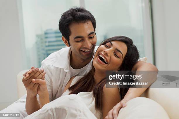 happy young couple relaxing on sofa - young couple holding hands stock pictures, royalty-free photos & images