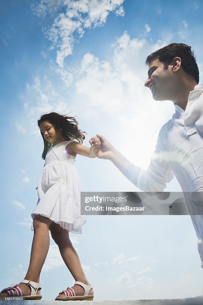 Father helping daughter (6-7) walking on wall