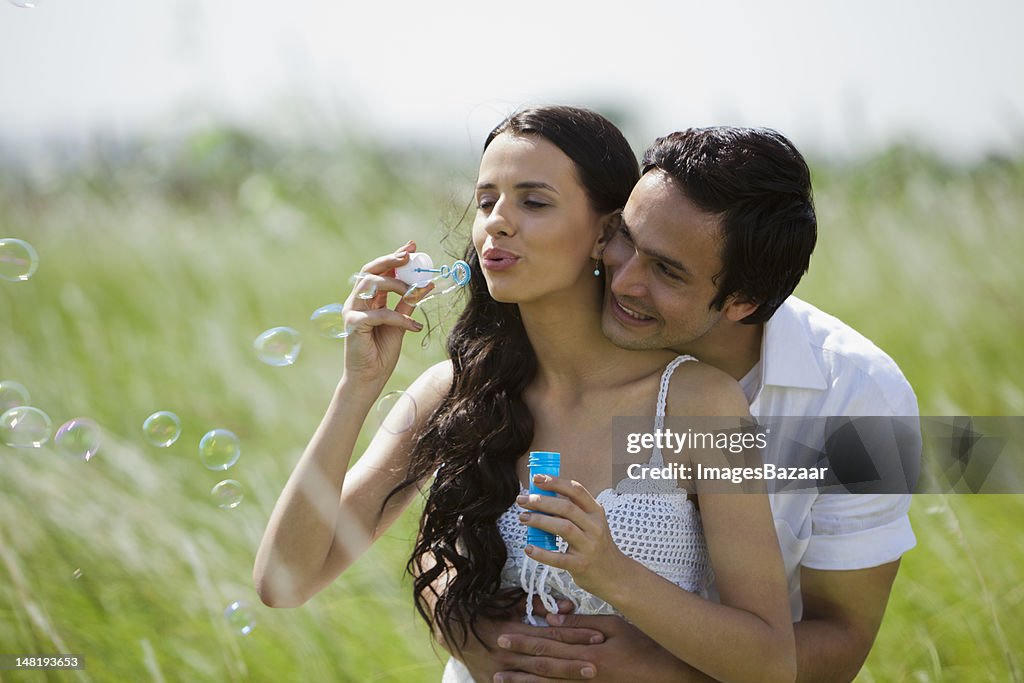 Young couple embracing and blowing bubbles