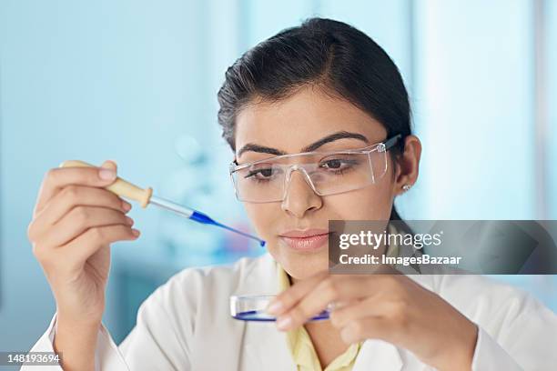 young woman in laboratory dripping liquid on petri dish - india lab stockfoto's en -beelden