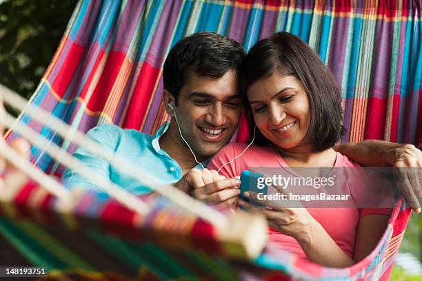 couple listening to mp3 player in hammock - young man listening music and relaxing in hammock stock pictures, royalty-free photos & images