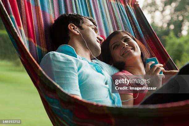 couple listening to mp3 player in hammock - young man listening music and relaxing in hammock stock pictures, royalty-free photos & images
