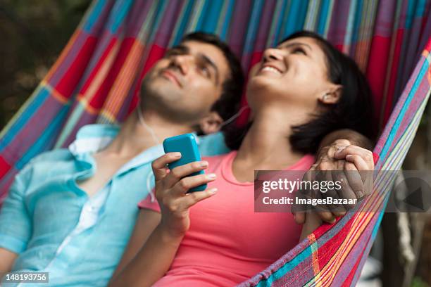 couple listening to mp3 player in hammock - young man listening music and relaxing in hammock stock pictures, royalty-free photos & images