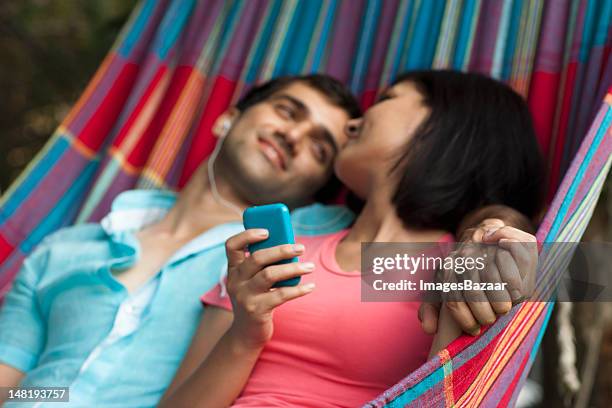 couple listening to mp3 player in hammock - young man listening music and relaxing in hammock stock pictures, royalty-free photos & images