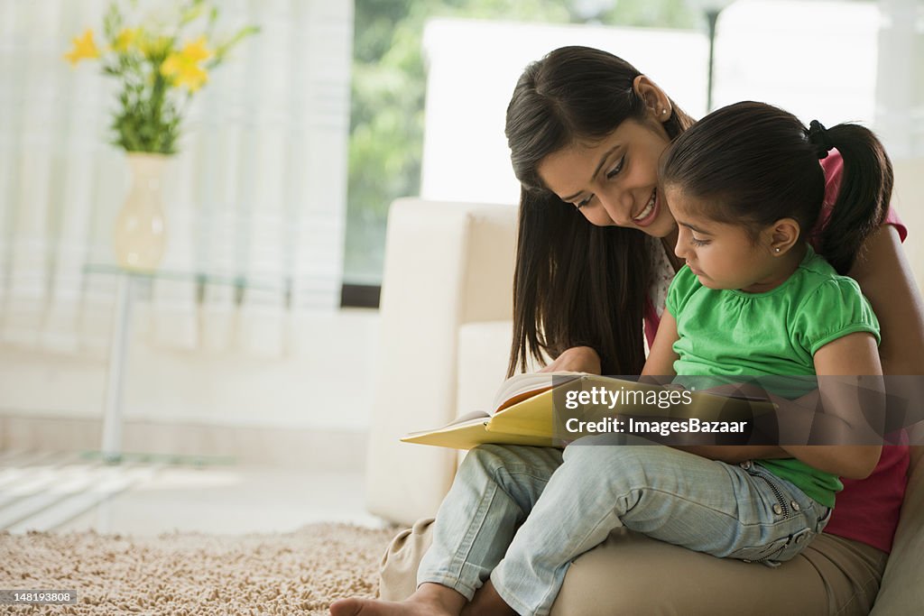 Mother reading book with daughter (6-7)