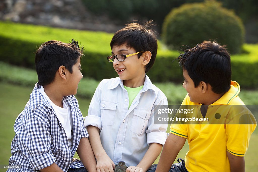 Tree boys (6-7) talking in park