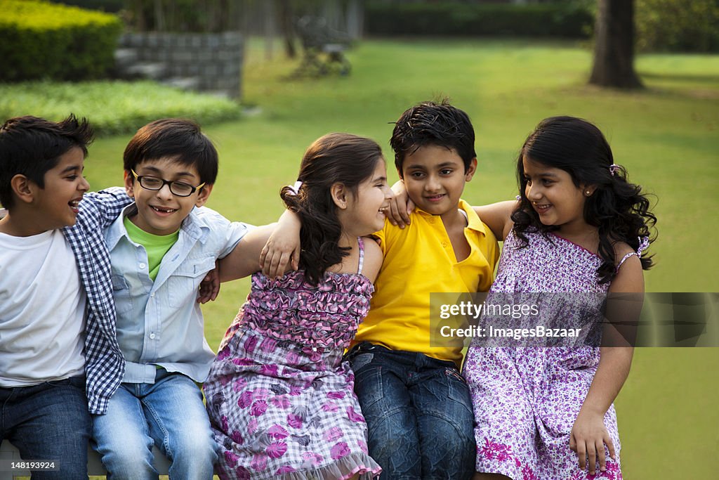 Bambini (6-7, 8-9) seduto sulla panchina nel parco