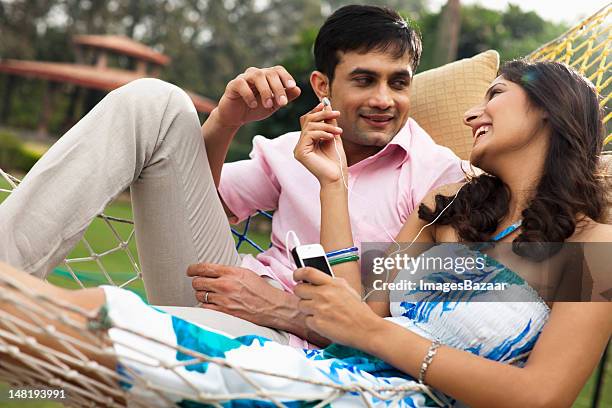 young couple listening to mp3 player in hammock - young man listening music and relaxing in hammock stock pictures, royalty-free photos & images