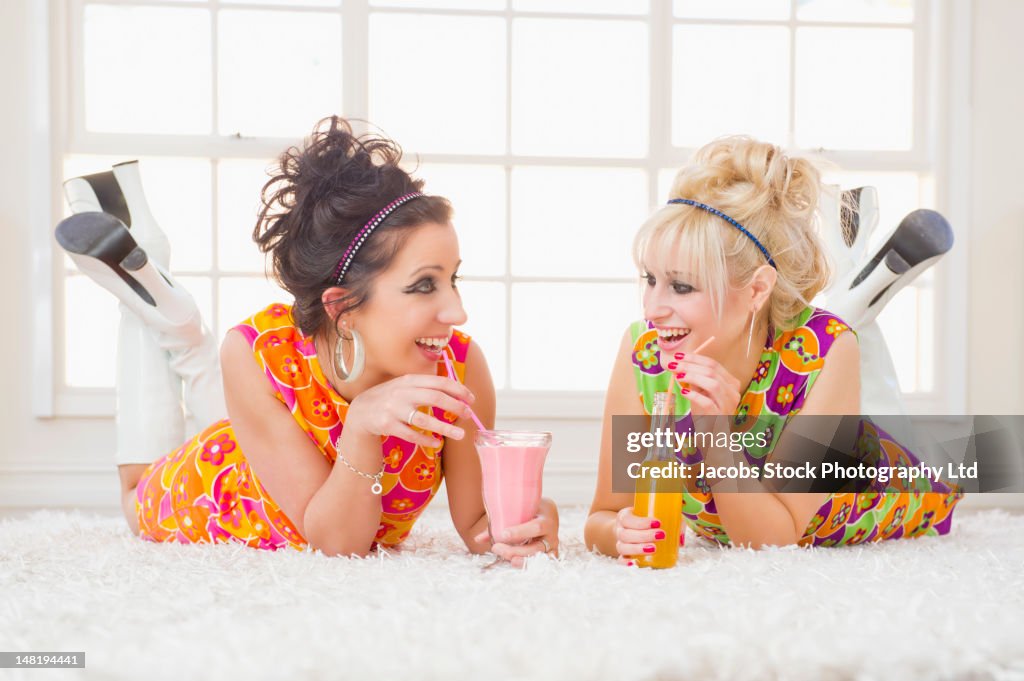 Friends in nostalgic dresses drinking and laying on floor