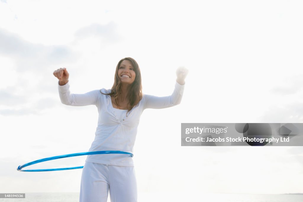 Hispanic woman playing with hula hoop