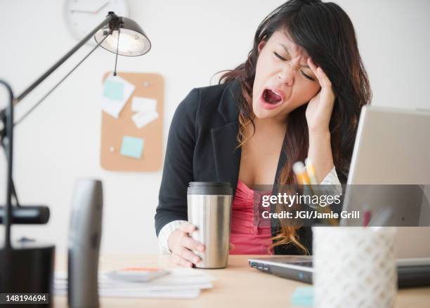 pacific islander businesswoman yawning at desk - yawn office stockfoto's en -beelden