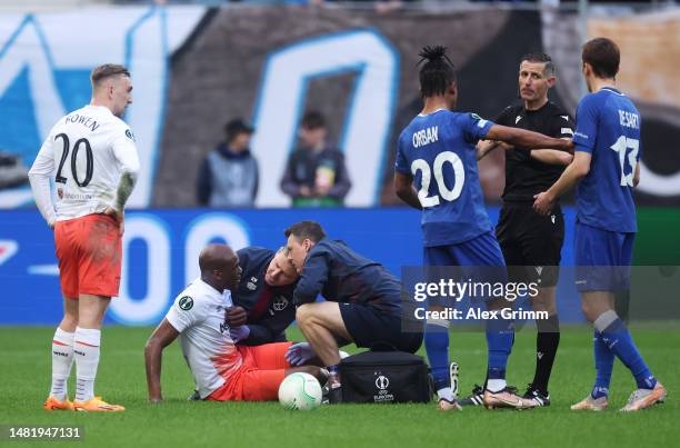 Angelo Ogbonna of West Ham United receives medical treatment whilst Match Referee Tasos Sidiropoulos speaks with Gift Orban and Julien de Sart of KAA...