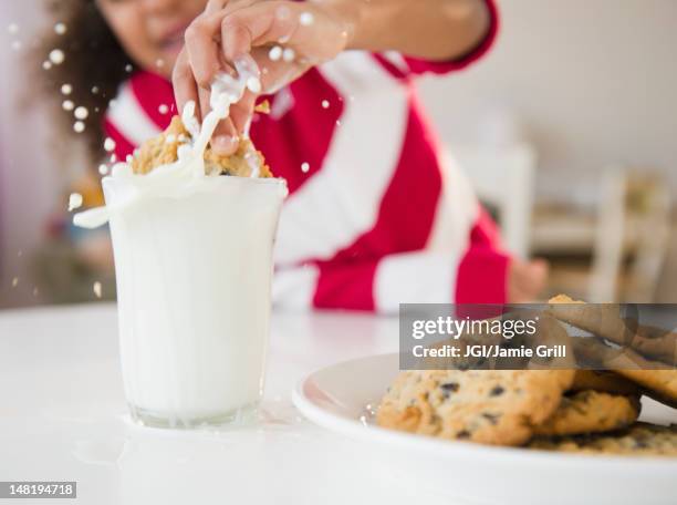 mixed race girl dunking cookie into milk - milk and cookies stock pictures, royalty-free photos & images