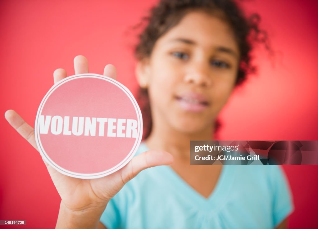 Mixed race girl holding volunteer sticker