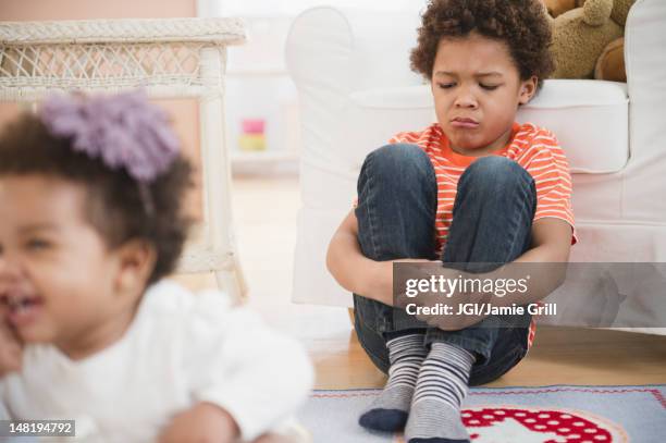 sad black boy sitting in living room - brother jealous stock pictures, royalty-free photos & images