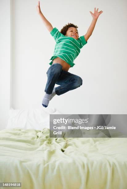 black boy jumping on bed - children jumping bed stock-fotos und bilder