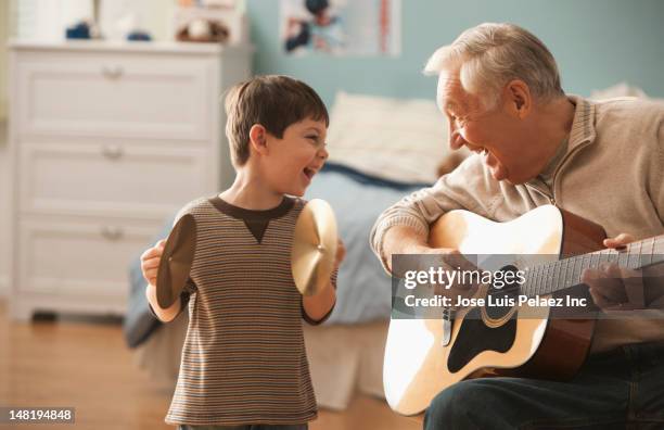 caucasian man and grandson playing musical instruments together - musikalische begleitung stock-fotos und bilder