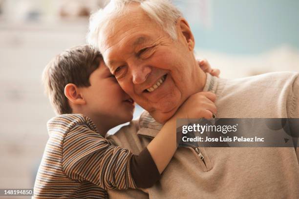 caucasian boy telling grandfather a secret - child whispering stock-fotos und bilder
